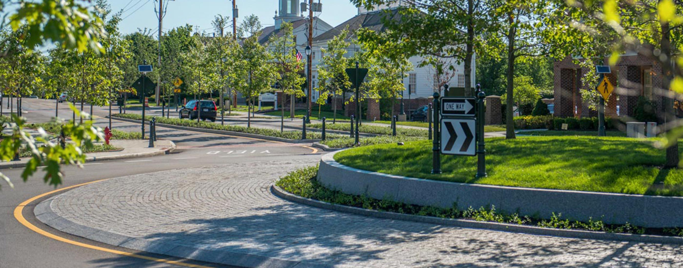 The center of New Albany, Ohio central roundabout, designed by OHM Advisors, is anchored by trees and a low granite wall.