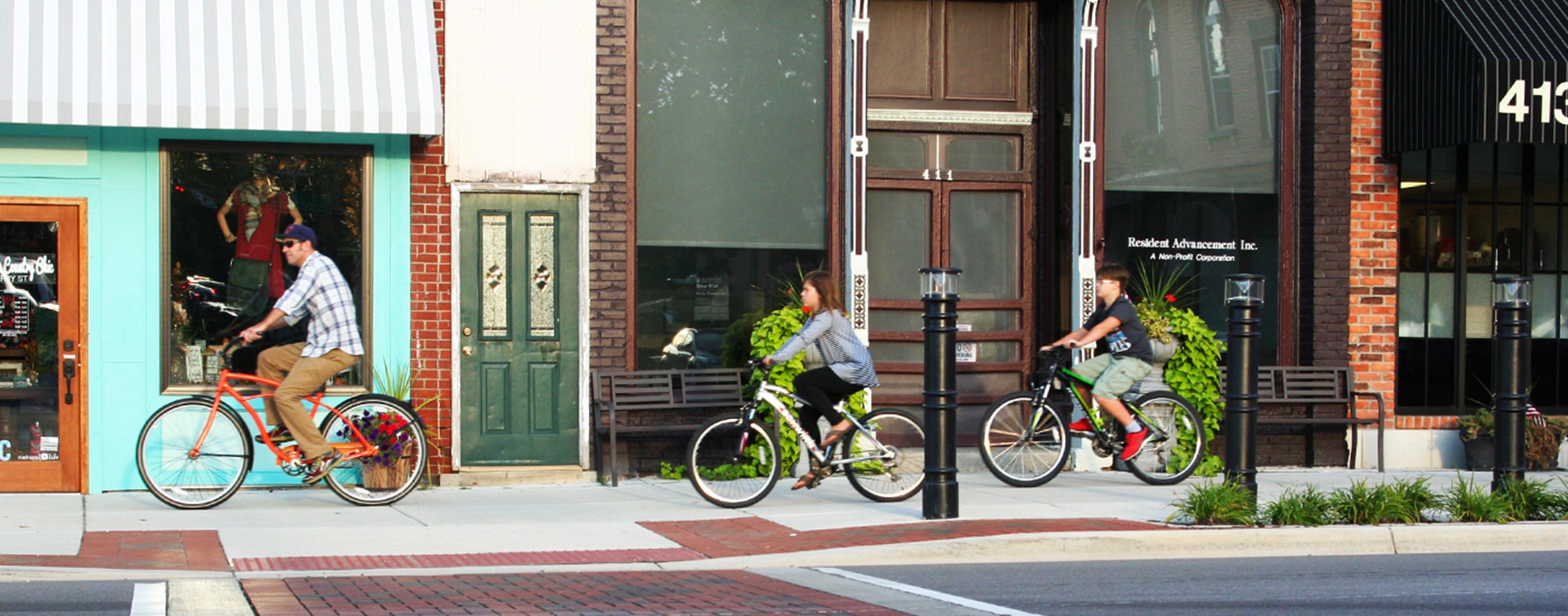 A family enjoys a bike ride along Fenton, Michigan’s new downtown streetscape, a project led by OHM Advisors.
