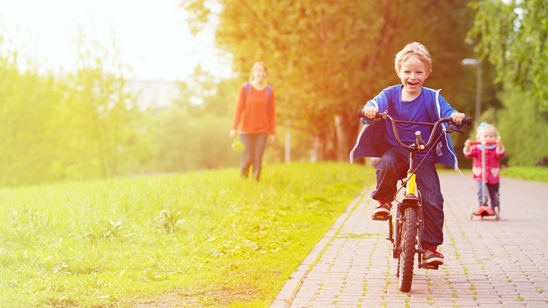 Walkability - boy bike riding down sidewalk