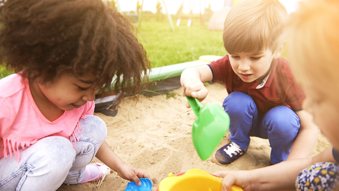 Young children play in a sandbox.