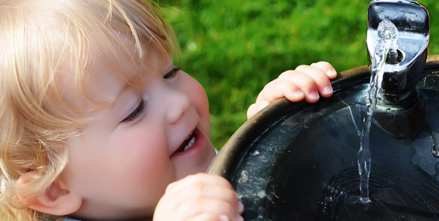 Child drinking from water fountain. 