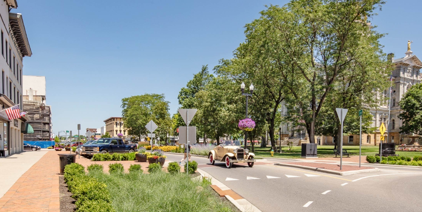 An old car drives through Newark, Ohio's roundabout and streetscape.