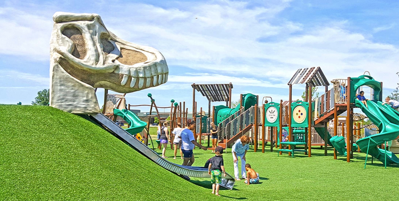 Children play on a dinosaur slide at the Veterans Memorial Park.