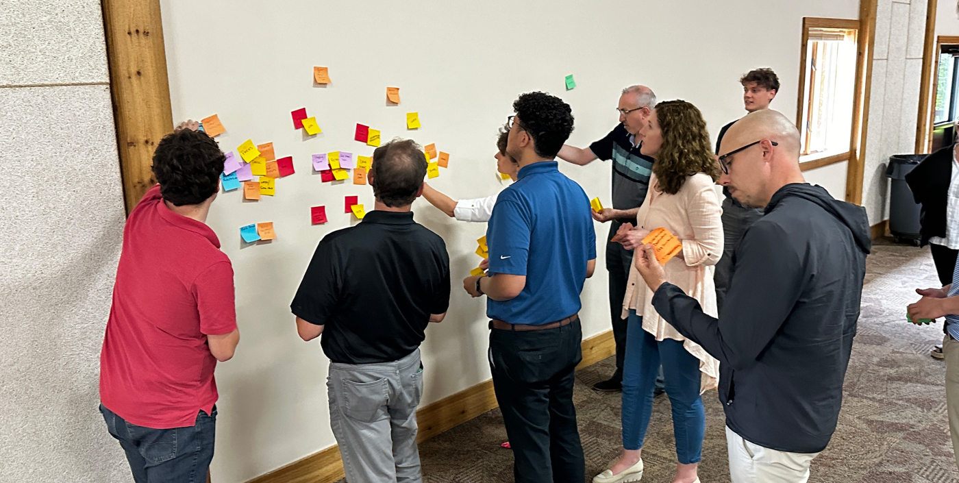 Group of community members collaborating with a wall of sticky notes