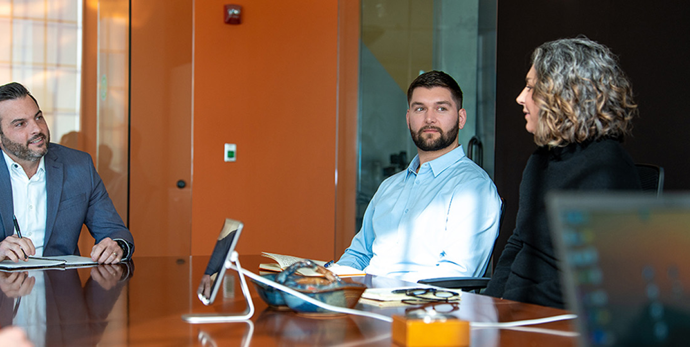 Office gentleman with beard looking at co-worker at conference table