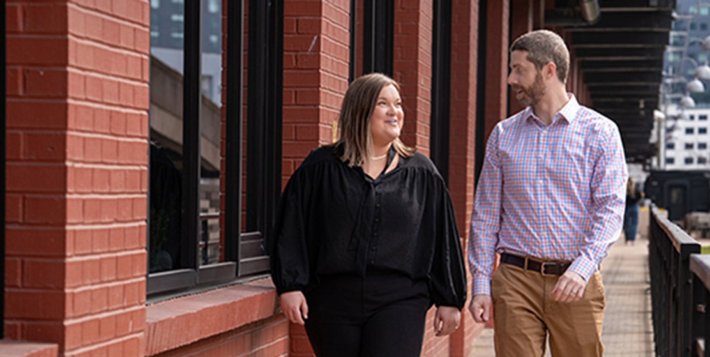 2 Employees walking by a red brick building