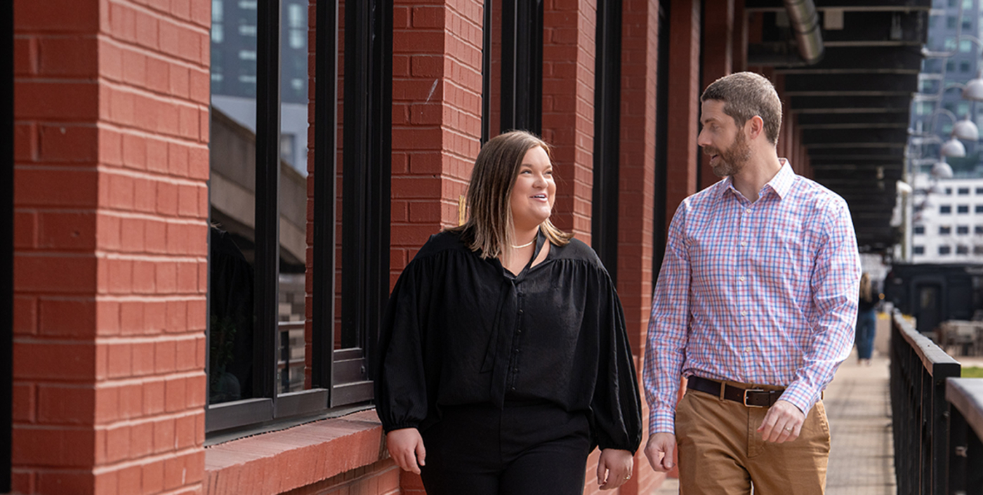 Male and female colleagues walking along a red brick building in Nashville