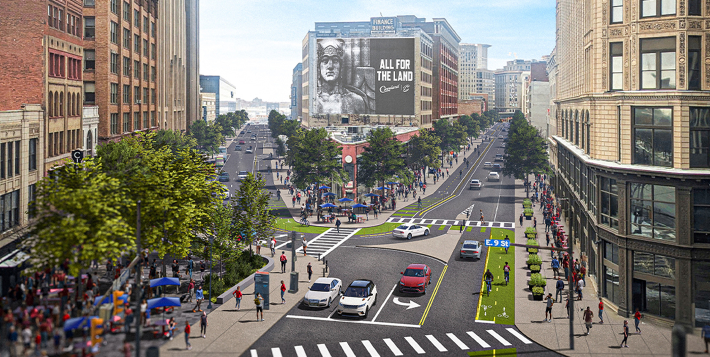 Two one-way city streets lined with trees, bike paths and people walking