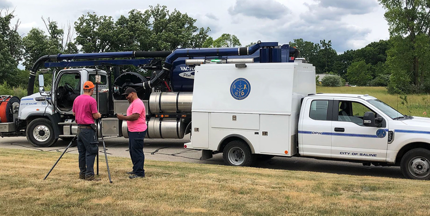 Two OHM Advisors survey employees in front of two trucks