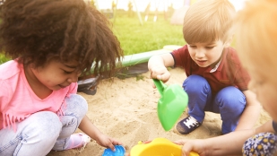 Young children play in a sandbox.