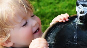 Child drinking from water fountain. 