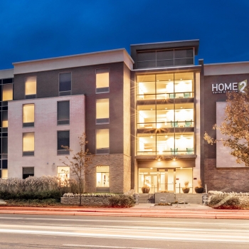 A nighttime view of the modern Hilton HOME2 Hotel, designed by OHM Advisors.