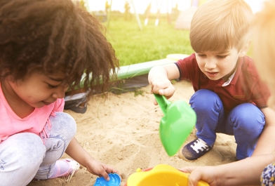 Young children play in a sandbox.