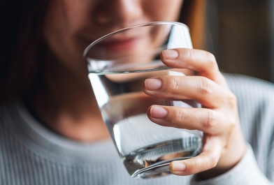A woman drinks water from a glass. 