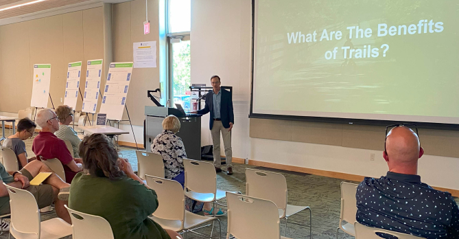 Man presenting at a public meeting on the benefits of trails 