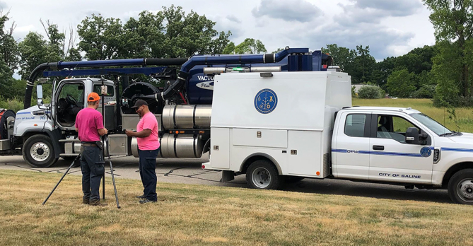Two OHM Advisors survey employees in front of two trucks