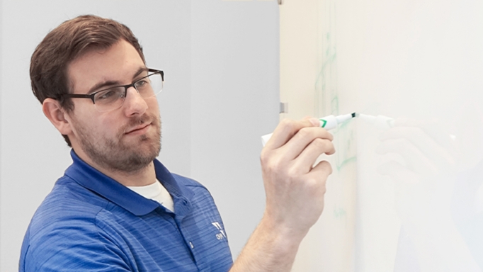 OHM Advisors offers staff ongoing training such as this best-practice sharing session with man writing on whiteboard.