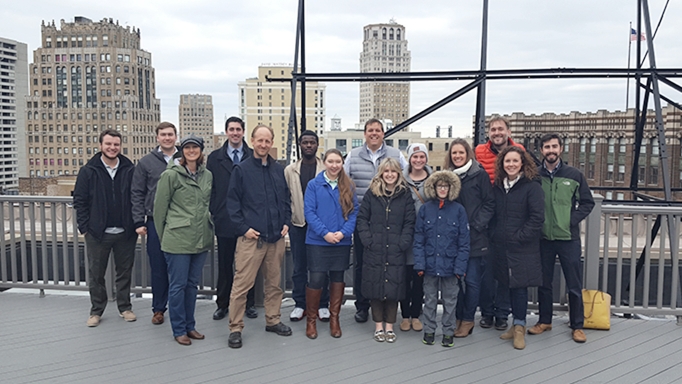 OHM Advisors' Detroit office staff on the roof of their building with downtown skyline in background