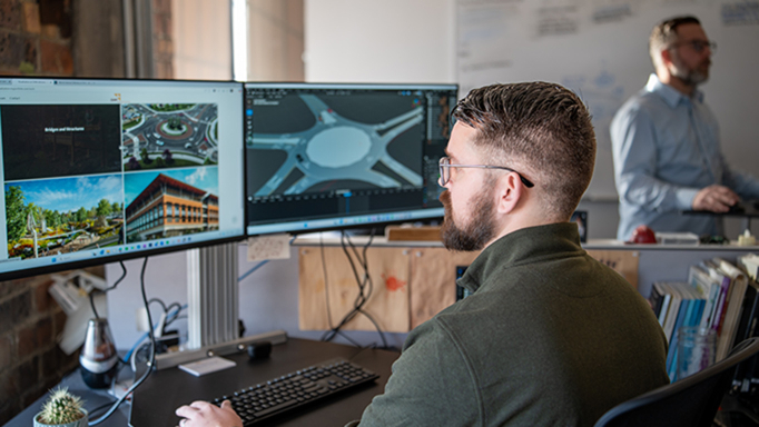Male employee looking at renderings on his computer monitor. 