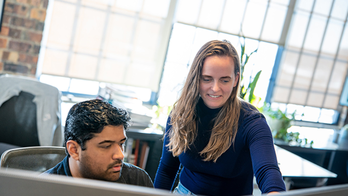 Two employees look at a computer screen 